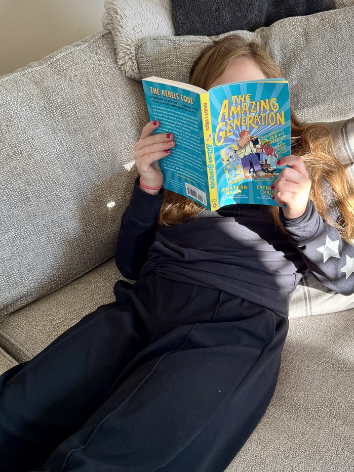 A girl stretched out on the couch, deep in a chapter book
